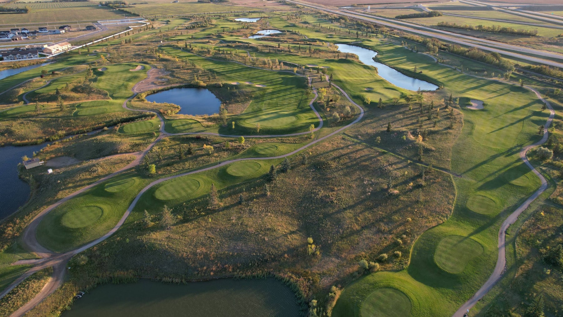An aerial view of The Legends Golf Club in Warman, showcasing its modern layout of winding fairways and sparkling water features. An aerial view of The Legends Golf Club in Warman, showcasing its modern layout of winding fairways and sparkling water features.