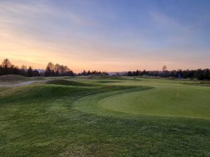 Golden-hour glow over Riverway’s mounded fairways and smooth greens - classic links-style shaping in full view.