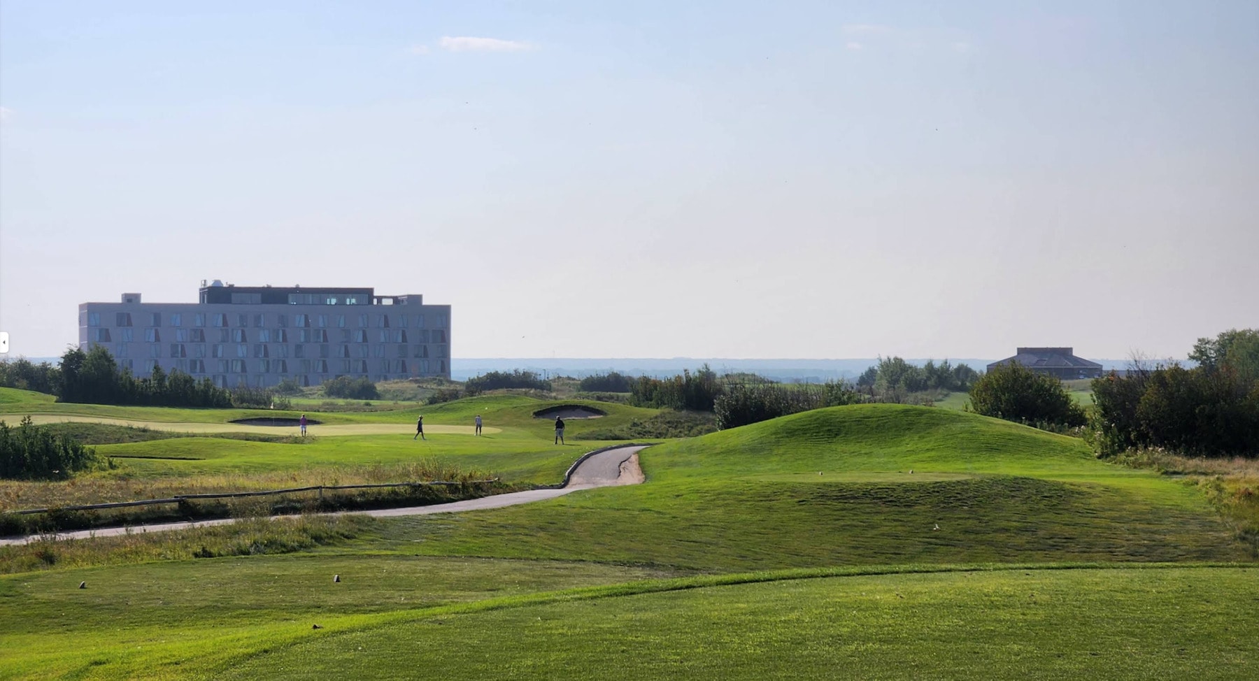 Golfers enjoy a sunny round at Dakota Dunes Golf Links, with the modern Dakota Dunes Resort rising beyond the rolling prairie fairways. Golfers enjoy a sunny round at Dakota Dunes Golf Links, with the modern Dakota Dunes Resort rising beyond the rolling prairie fairways.