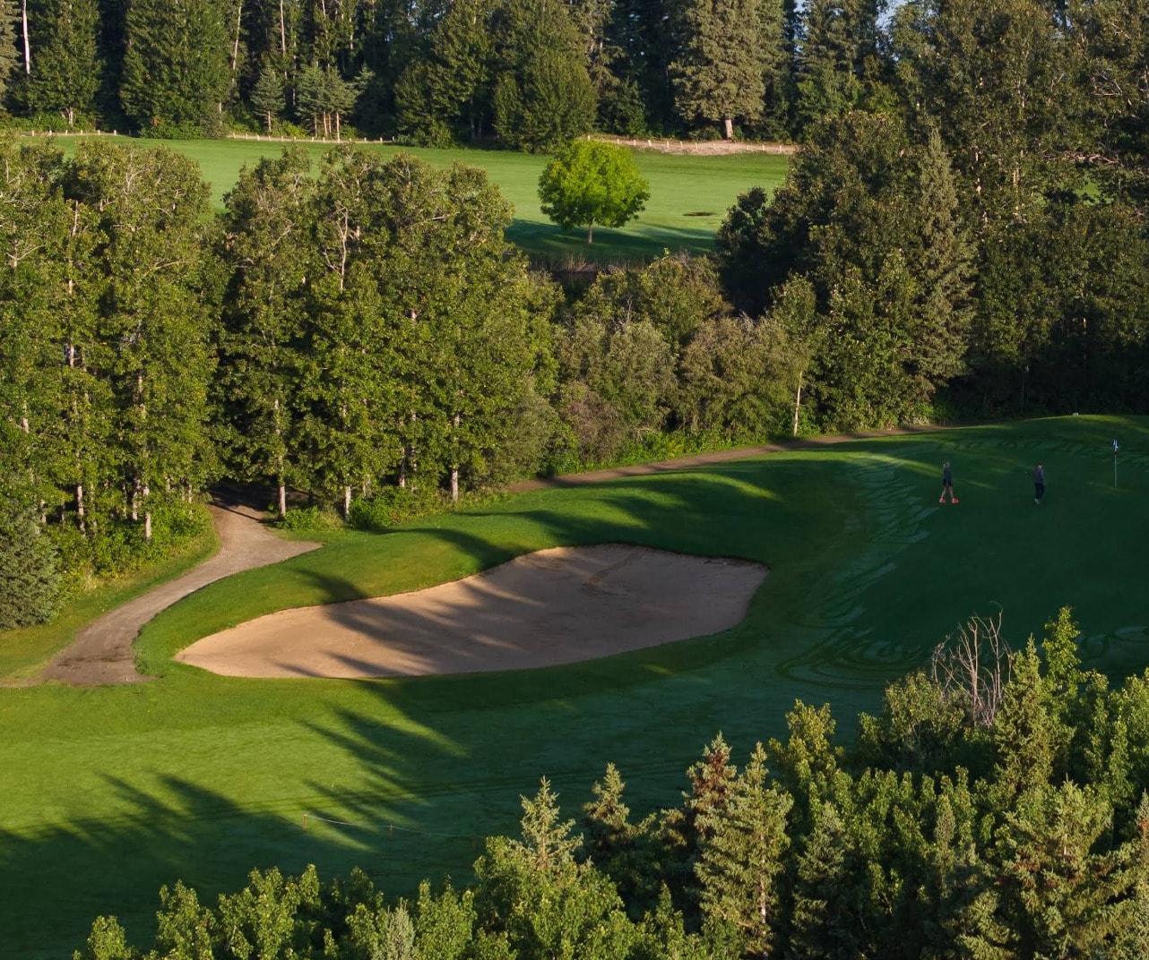 Morning sunlight over a green and bunker at Candle Lake Golf Resort, surrounded by dense northern forest. Morning sunlight over a green and bunker at Candle Lake Golf Resort, surrounded by dense northern forest.