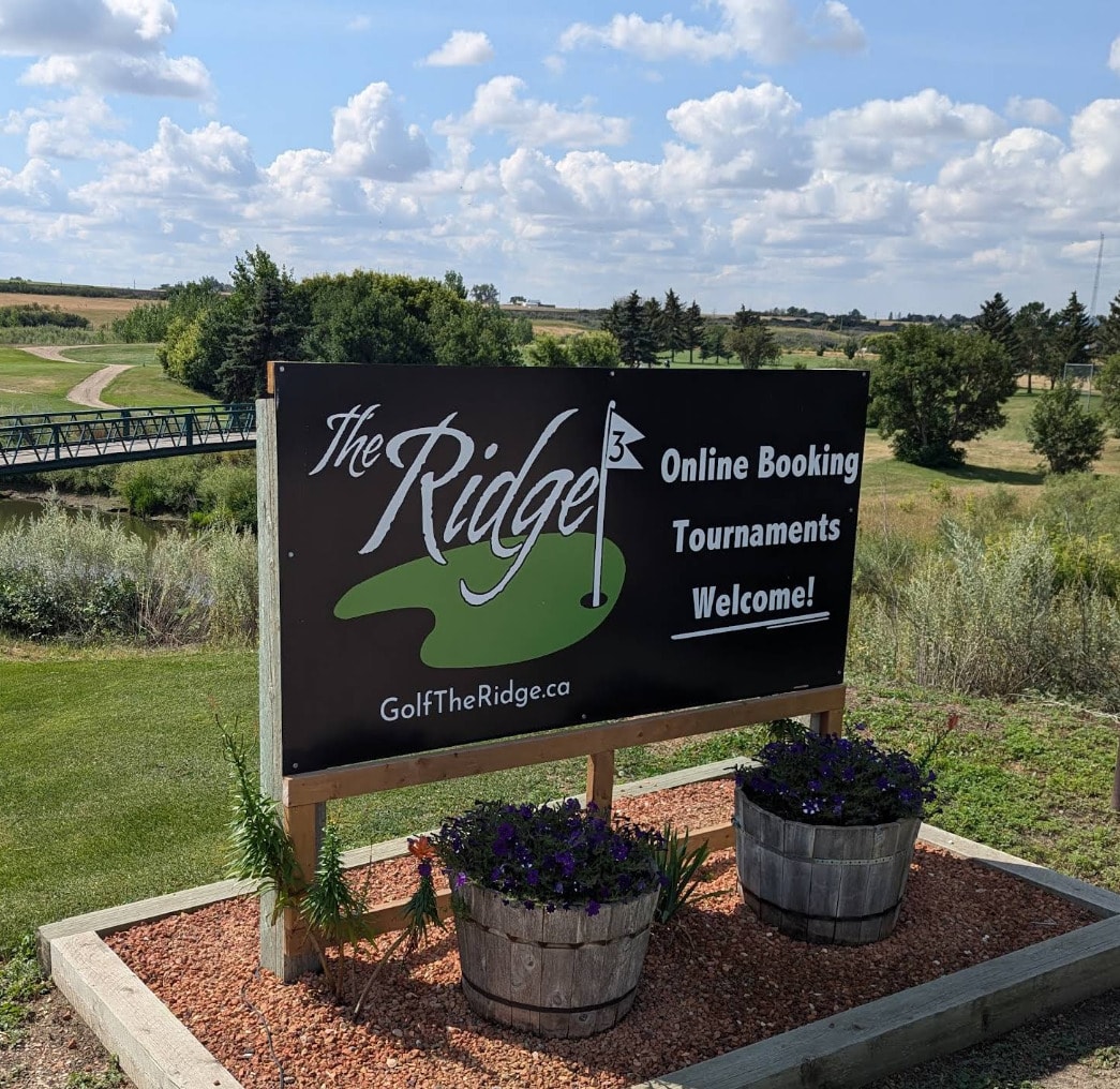 Sign welcoming golfers to The Ridge - The River Course in Moose Jaw, with scenic fairways stretching beyond. Sign welcoming golfers to The Ridge - The River Course in Moose Jaw, with scenic fairways stretching beyond.