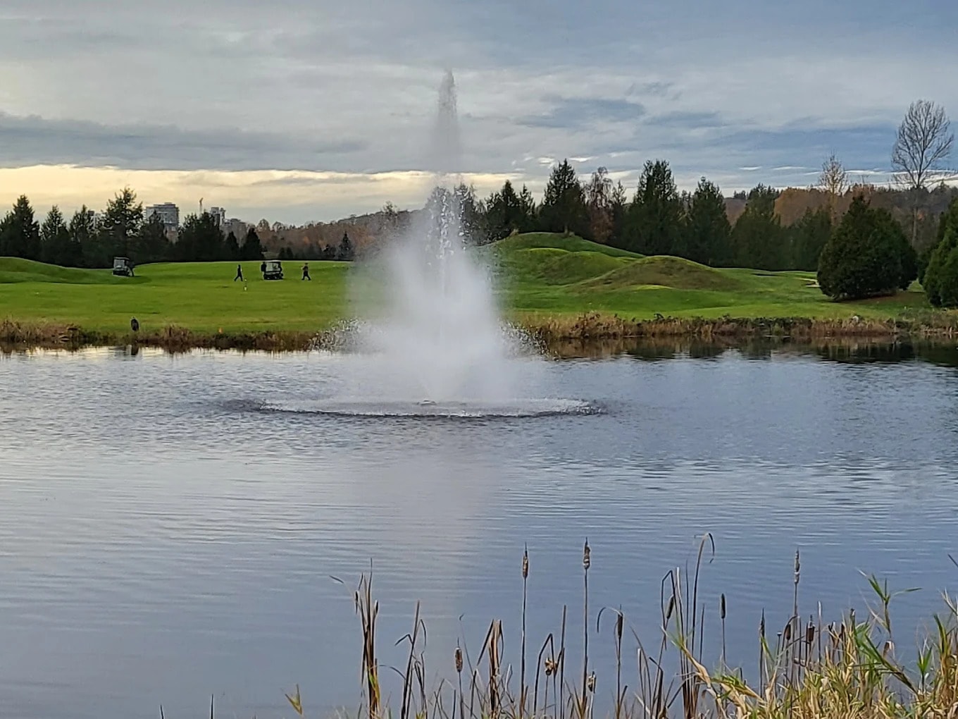 Signature fountain at Riverway Golf Course, with rolling fairways and mounded greens in the backdrop - seen from the clubhouse area. Signature fountain at Riverway Golf Course, with rolling fairways and mounded greens in the backdrop - seen from the clubhouse area.